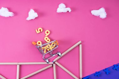 alışveriş sepeti ile çeşitli sayılar renkli kalemler için pembe üzerinde matematiksel ifade ile düzenlenmiş cliff sürme
