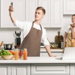 Boyfriend taking selfie with smartphone in kitchen