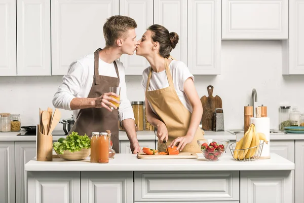 若いカップルがキッチンでサラダを調理しながらキス — ストック写真