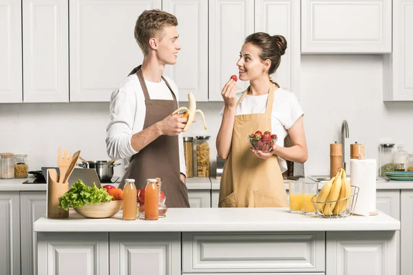 Pareja Joven Comiendo Frutas Saludables Mirándose Cocina —  Fotos de Stock