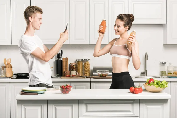 Fidanzato Scattare Foto Fidanzata Con Bottiglie Succo Sano Cucina — Foto Stock