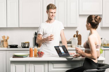 dizüstü yüklü LinkedIn sayfa ile kullanma ve erkek mutfakta bakarak kız