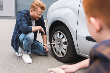 Lastik tekerlekli anahtar, yanında oturan oğlu ile arabada değişen baba