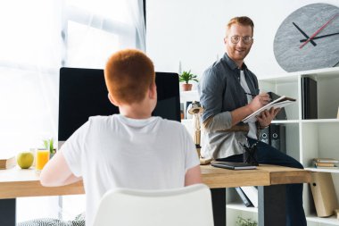 Defter ve evde bilgisayarı kullanan oğlu seyir ile kalem tutan baba