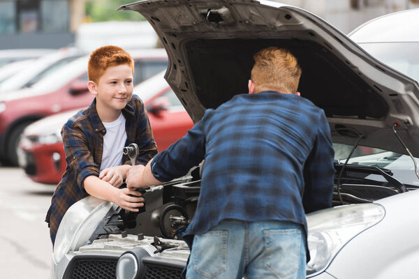 son giving tool for repairing car to father