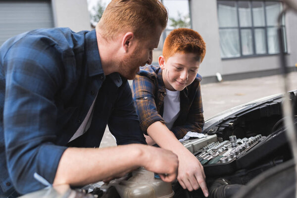 father and son repairing car with open hood together