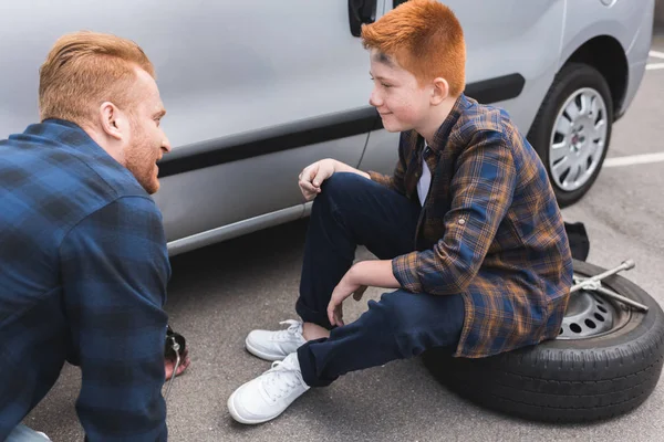 Pai Filho Trocando Pneu Carro Com Macaco Chão Olhando Para — Fotografia de Stock