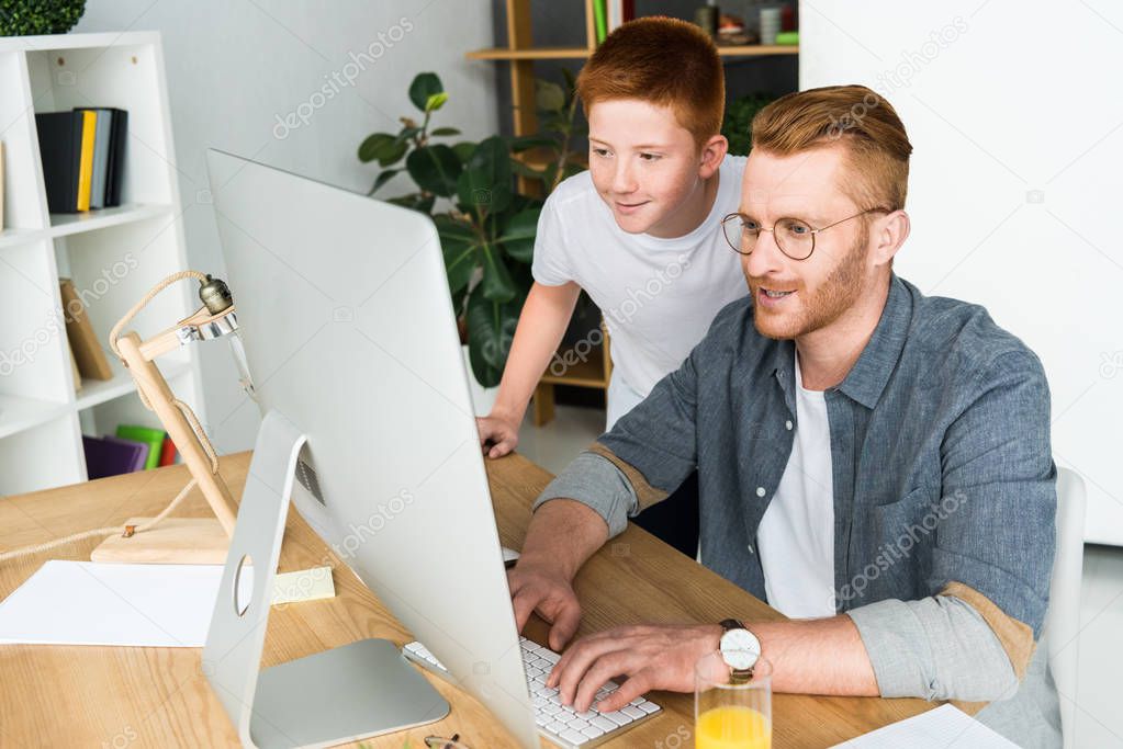 father and son looking at computer at home