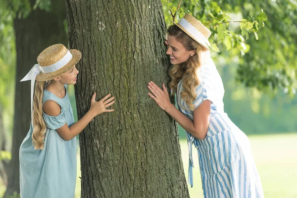 Leende Mor Och Dotter Stråhattar Posing Nära Träd — Gratis stockfoto