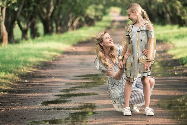 Блондинка Мати Чарівна Дочка Позує Прозорих Плащах Мокрій Дорозі Парку — стокове фото