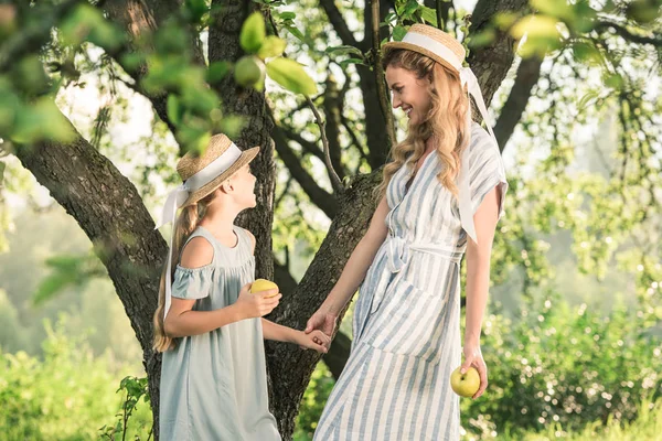 Hermosa Madre Feliz Hija Sombreros Paja Con Manzanas Mirándose — Foto de Stock