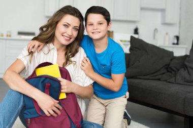 geri okul kavramı kitap ve sırt çantası evde, Anne sarılma boy gülümseyerek portresi