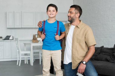 Baba ve oğul evde, sırt çantası ile geri okul kavramı gülümseyen