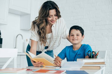 Anne yardım gülümseyen oğul evde mutfak ödev ile portresi