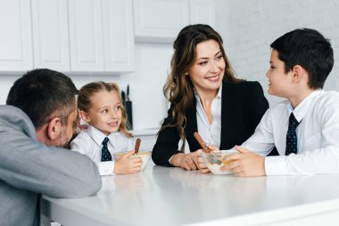 Aile takım elbise ve okul üniforması birlikte mutfakta kahvaltı