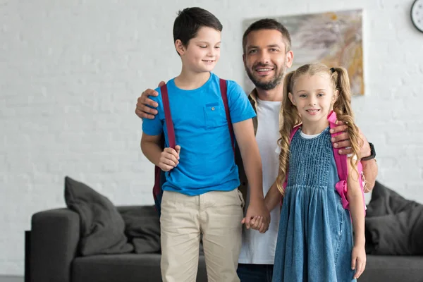 Porträt Eines Lächelnden Vaters Der Hause Kinder Mit Rucksäcken Umarmt — Stockfoto