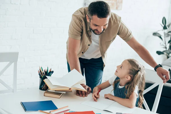 Padre Guardando Piccola Figlia Facendo Compiti Tavola Casa — Foto stock gratuita