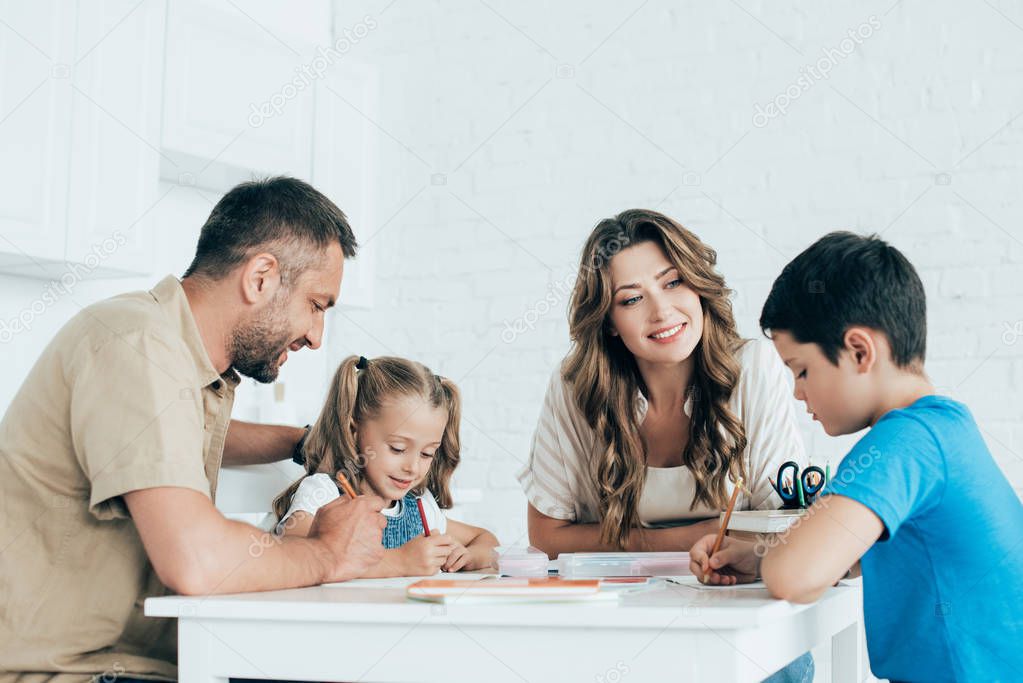 parents helping children with homework at table at home