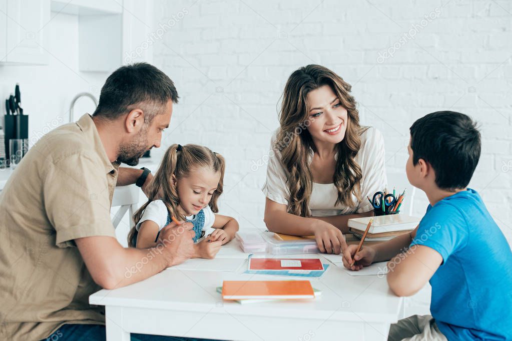 parents helping children with homework at table at home