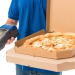 Recortado tiro de repartidor hombre sosteniendo pizza en cajas y terminal móvil aislado en blanco