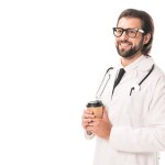 Bel dottore sorridente che tiene il caffè per andare e distogliere lo sguardo isolato sul bianco