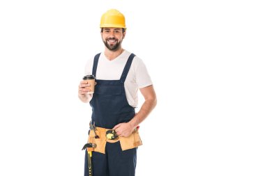 handsome happy workman in tool belt holding paper cup with coffee to go and smiling at camera isolated on white clipart
