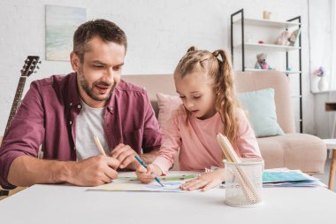 cheerful dad and daughter having fun and drawing at home clipart