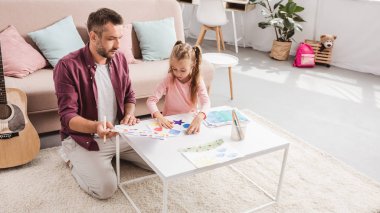 Baba ve kızı eğleniyor ve beyaz masaya çizim