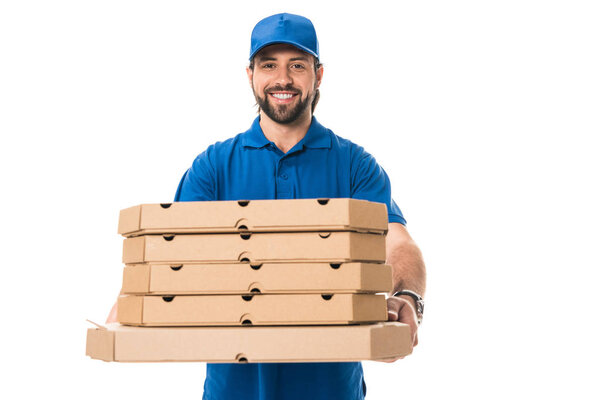handsome happy delivery man holding boxes with pizza and smiling at camera isolated on white