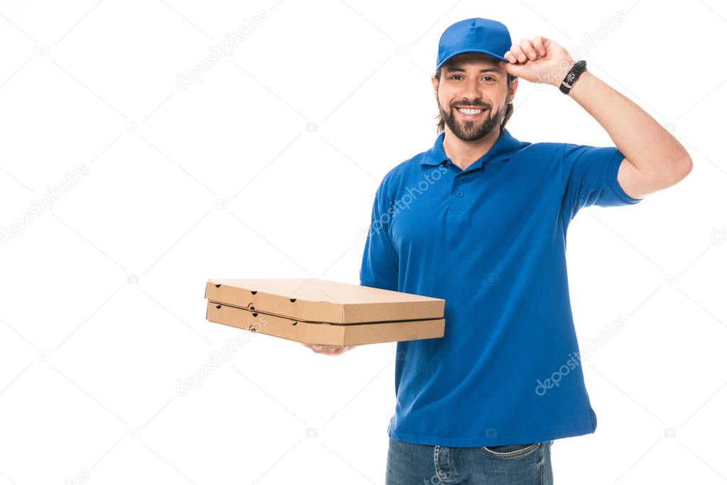 happy delivery man holding boxes with pizza adjusting cap, smiling at camera isolated on white