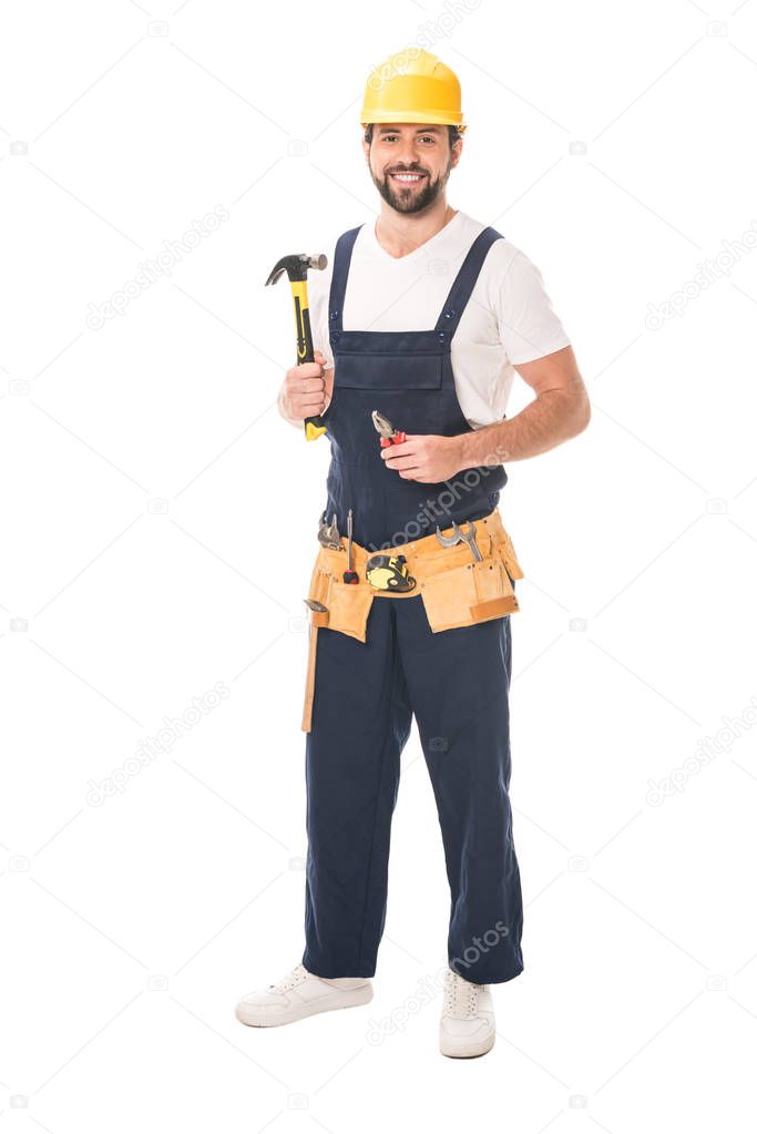 full length view of handsome repairman holding tools and smiling at camera isolated on white