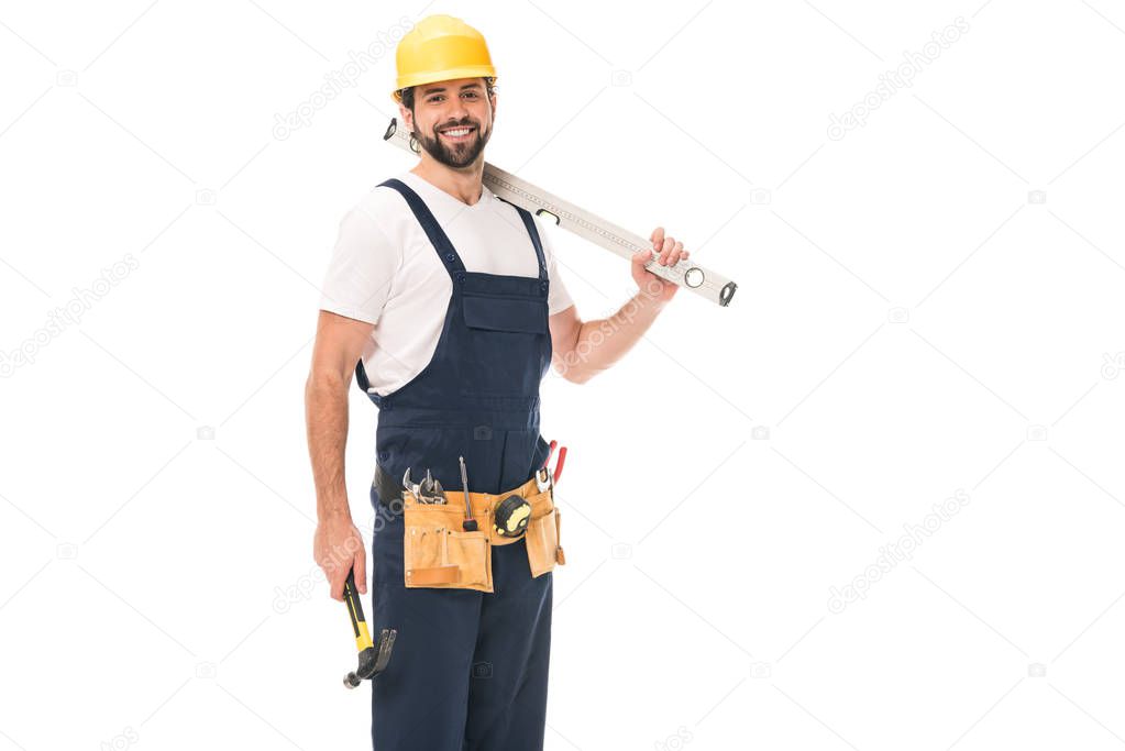 handsome happy workman holding level tool and hammer, smiling at camera isolated on white