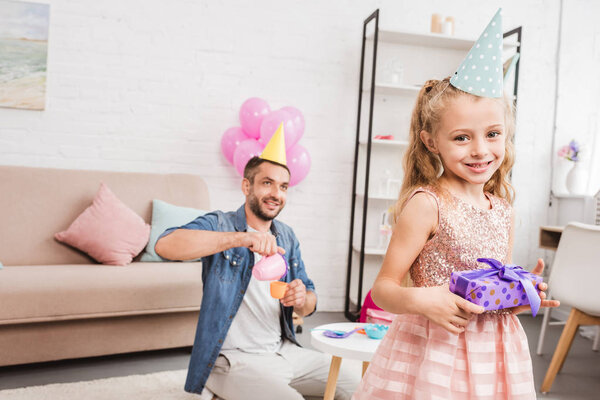 father and daughter in cone hats playing tea party at home