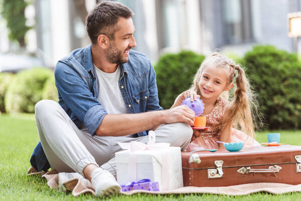 father and daughter playing tea party at lawn