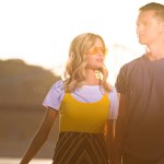 Young couple standing on river beach during sunset