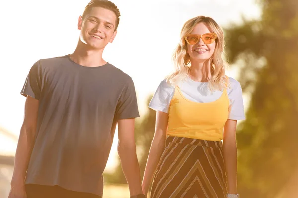 Sonriente Joven Pareja Cogida Mano Playa Del Río Durante Atardecer — Foto de stock gratis