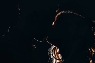 Karanlıkta heteroseksüel çift öpüşme siluetleri yan görünüm