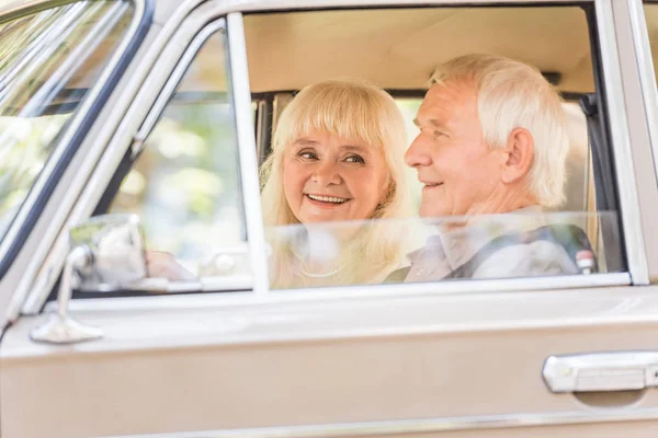 ベージュのビンテージ車に年配のカップルの側面図 — ストック写真