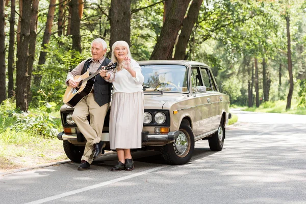 Seniorin Mit Mann Spielt Gitarre Auto Wald Gelehnt — Stockfoto