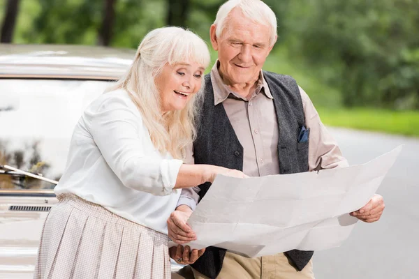 幸福的老年夫妇持有地图和倾斜的复古车 — 图库照片