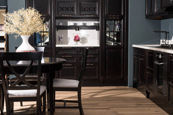 интерьер современной столовой с черной мебелью и вазой из сушеных цветов на столе
