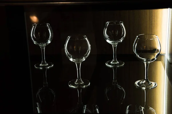 different glasses on shelf in kitchen with dark light
