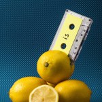 Fresh yellow lemons with vintage audio cassette on blue