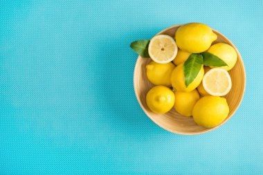 Turkuaz arka plan üzerinde ahşap plaka yapraklarla taze limon üstten görünüm
