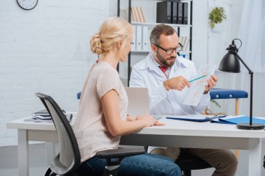 female patient having appointment with chiropractic in clinic clipart