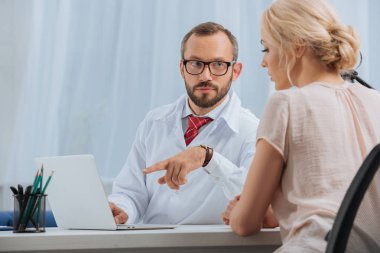 fizyoterapist beyaz ceket konuşmayı bayan hasta ile hastane içinde laptop ile işyerinde