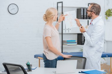 Chiropractic beyaz önlük gösteren insan vücudu düzeni hastanede bayan hasta için