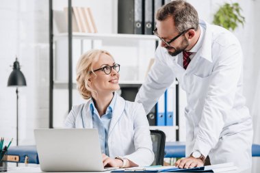 Fizyoterapistler birbirine Kliniği içinde laptop ile işyerinde bakarak beyaz kat olarak gülümseyen 