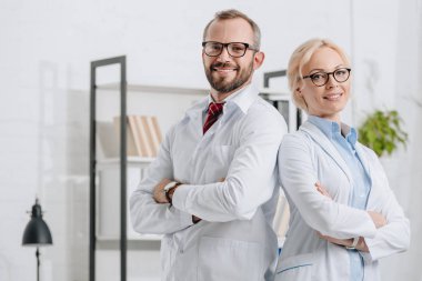 portrait of smiling physiotherapists in white coats looking at camera in clinic clipart