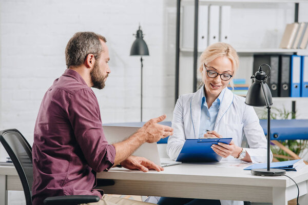 пациент разговаривает с физиотерапевтом во время приема в больнице

